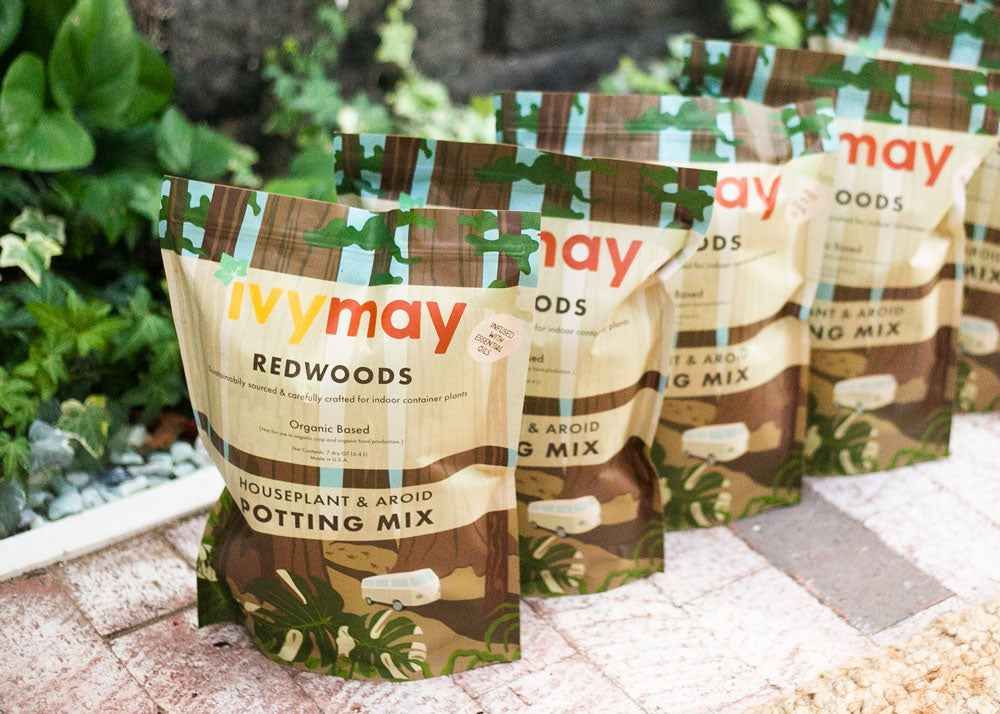 Three bags of IvyMay Redwoods Houseplant & Aroid Peat-Free Potting Mix on a a brick floor inside of the IvyMay Hideaway.